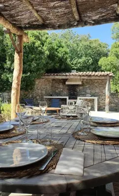 a wooden table with plates and glasses on a patio at Les Bergeries de Piazzagina in Piediquarciu
