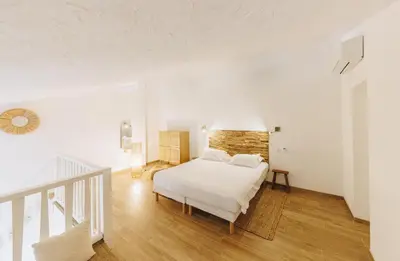 a white bedroom with a bed and a staircase at Oro Biancu in Lucciana