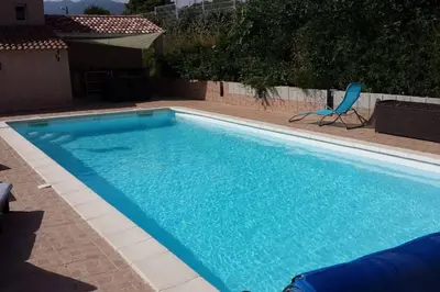 a large blue swimming pool with a chair next to it at Pavillon T2 proche ville dans petite résidence in Cuttoli-Corticchiato