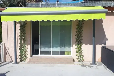 a building with a green awning with ivy on it at Pavillon T2 proche ville dans petite résidence in Cuttoli-Corticchiato