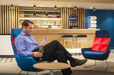 a man sitting in a chair with a glass of wine at Holiday Inn Express Ajaccio by IHG in Ajaccio