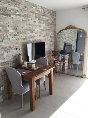 a dining room with a table and chairs and a mirror at Mini-villa mitoyenne de type F2 proche Golfe de Lava in Appietto