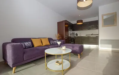 a living room with a purple couch and a table at Mini-villa mitoyenne de type F2 proche Golfe de Lava in Appietto