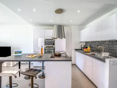 a kitchen with white cabinets and a island with bar stools at Apartment Domaine d'Arca-2 by Interhome in Porto-Vecchio