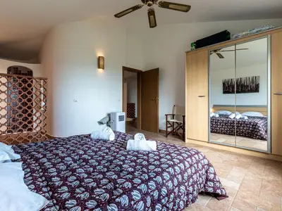 a bedroom with a large bed and a large mirror at Villa Villa Pavellone by Interhome in Porto-Vecchio