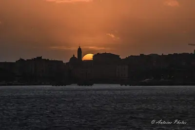 a view of a city with the sun setting over the water at Studio centre ville in Ajaccio