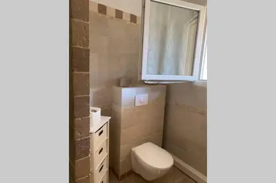 a bathroom with a toilet and a sink and a window at Suite spacieuse avec accès piscine in Ghisonaccia