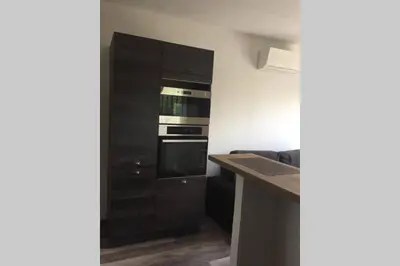 a kitchen with a black cabinet and an oven at Suite spacieuse avec accès piscine in Ghisonaccia