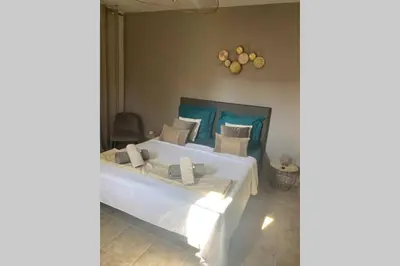 a bedroom with a large white bed with blue accents at Suite spacieuse avec accès piscine in Ghisonaccia
