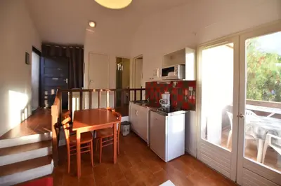 a kitchen with a table and a small kitchen with a table and chairs at Résidence U Nebbiu in Olmeta-di-Tuda