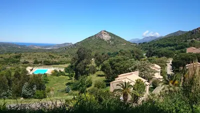 a view of a resort with mountains in the background at Résidence U Nebbiu in Olmeta-di-Tuda