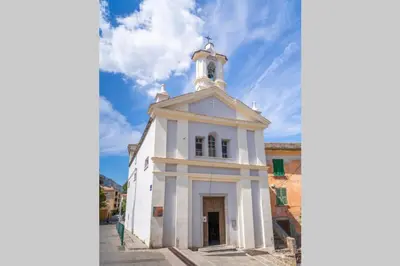 a white church with a tower on a street at Magnifique Grand 30m2 refait à neuf en 2025 lumineux 4 couchages hyper centre Corte 13 cours paoli wifi tv lave linge in Corte