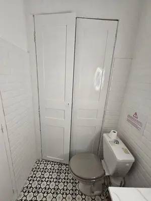a small bathroom with a toilet and a door at Magnifique Grand 30m2 refait à neuf en 2025 lumineux 4 couchages hyper centre Corte 13 cours paoli wifi tv lave linge in Corte