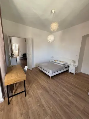 a bedroom with a bed and a wooden floor at Magnifique grand T3 refait à neuf en 2025 plein centre corte 13 cours paoli wifi écran plat lave linge 6 couchages in Corte