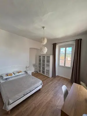 a bedroom with a bed and a table and a window at Magnifique grand T3 refait à neuf en 2025 plein centre corte 13 cours paoli wifi écran plat lave linge 6 couchages in Corte