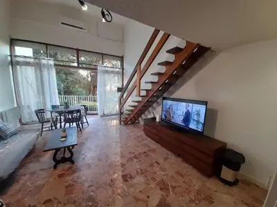a living room with a television and a dining table at PORTICCIO BRILOC APPART DUPLEX à 150m de la plage. in Porticcio