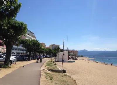 a beach with cars parked on it and people walking on it at Ajaccio magnifique T2 neuf 40m2 avec balcon au Trottel 4 couchages wifi Clim parking plage à pieds 100m in Ajaccio