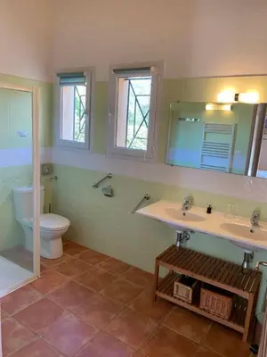 a bathroom with two sinks and a toilet and a mirror at Les Villas de Lava in Appietto