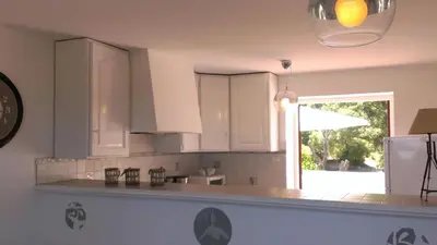 a kitchen with white cabinets and a clock on the wall at LES TERRASSES D ACQUACITOSA in SERRA DI FIUMORBO