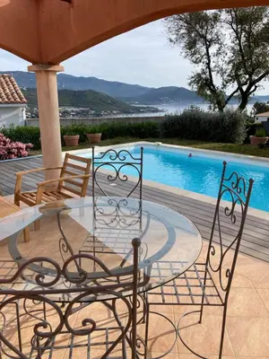 a couple of chairs sitting next to a swimming pool at Superbe villa avec piscine vue mer, proche plage et Porticcio in Pietrosella