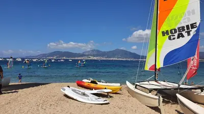 a group of boats on a beach with people in the water at Porticcio - Casa Corsa in Porticcio