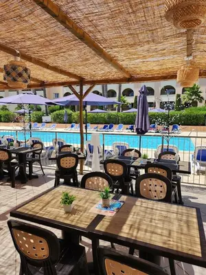 a patio with tables and chairs and a swimming pool at Corse Appartement vue mer - Linguizzetta - Marine de Bravone in Linguizzetta