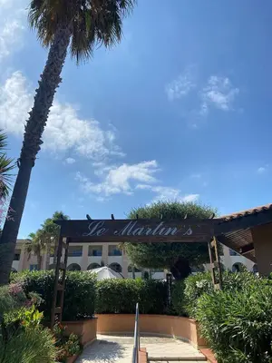 a sign in front of a building with a palm tree at Corse Appartement vue mer - Linguizzetta - Marine de Bravone in Linguizzetta