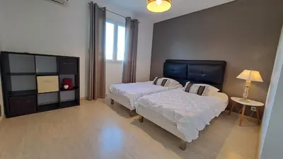 a bedroom with two beds and a table and a lamp at Très belle villa piscine jacuzzi grande propriété 10 pers in Belgodère