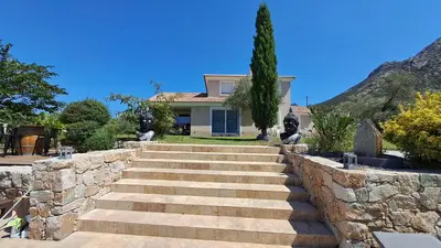 a house with a stone wall and stairs at Très belle villa piscine jacuzzi grande propriété 10 pers in Belgodère