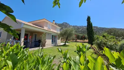 a house with a garden with a mountain in the background at Très belle villa piscine jacuzzi grande propriété 10 pers in Belgodère