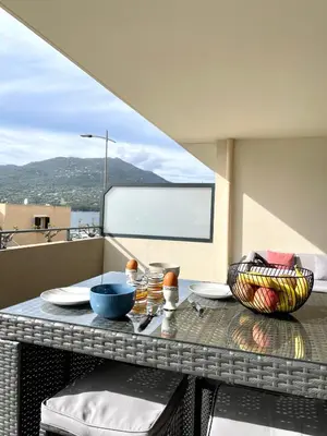 a table with plates and bowls on a balcony at T2 de standing front de mer in Propriano