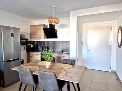 a kitchen with a wooden table with chairs and a refrigerator at T2 de standing front de mer in Propriano
