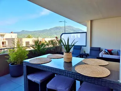 a balcony with a table and chairs and a screen at T2 de standing front de mer in Propriano