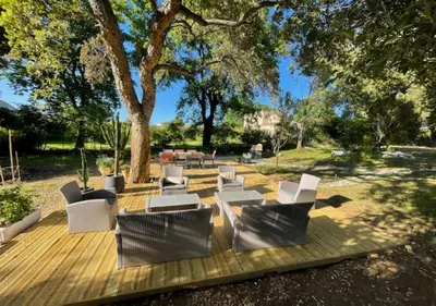 a wooden deck with white chairs and a tree at Résidence Poggiole in San-Nicolao