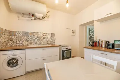 a kitchen with a washing machine and a table at Résidence Poggiole in San-Nicolao