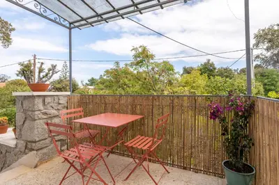 a table and chairs on a patio with a fence at Résidence Poggiole in San-Nicolao