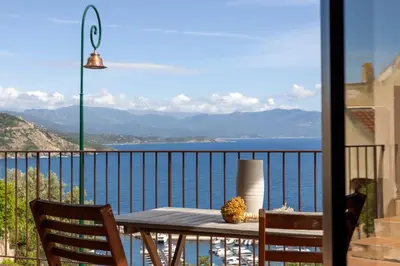 a table on a balcony with a view of the water at Résidence Eole in Cargèse