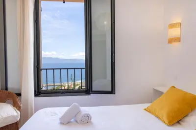 a bedroom with a window with a view of the ocean at Résidence Eole in Cargèse