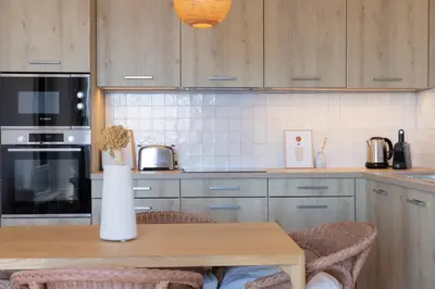 a kitchen with a wooden table with a vase on it at Résidence Eole in Cargèse