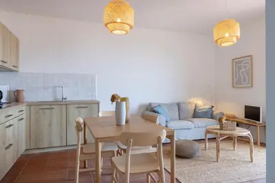 a kitchen and living room with a table and a couch at Résidence Eole in Cargèse