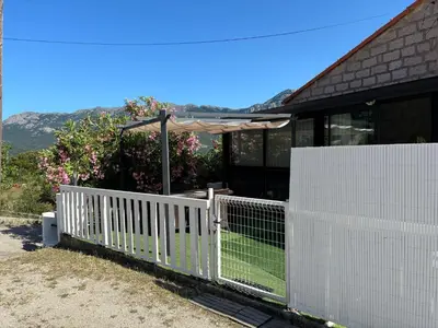 a white fence in front of a house with an umbrella at Appartement au calme à 15 minutes de Sartène in Foce
