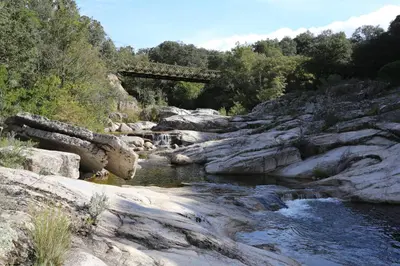 a bridge over a river with rocks and water at Appartement au calme à 15 minutes de Sartène in Foce