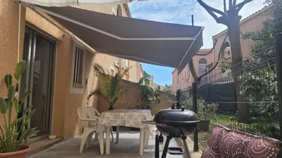 a grill on a patio with a table and chairs at Studio situé à 20 metres de la plage d Agosta Porticcio in Albitreccia