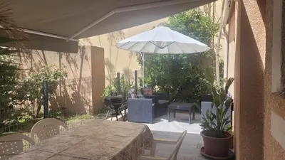 a patio with a table and a white umbrella at Studio situé à 20 metres de la plage d Agosta Porticcio in Albitreccia