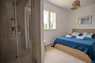 a bedroom with a bed and a glass shower at Villa Clara piscine chauffée in Prunelli-di-Fiumorbo