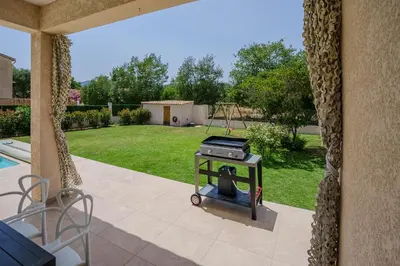 a grill sitting on a patio next to a yard at Villa Camille in Prunelli-di-Fiumorbo