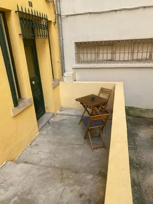 a wooden table and a chair sitting outside of a building at Superbe appartement en plein coeur d'Ajaccio in Ajaccio