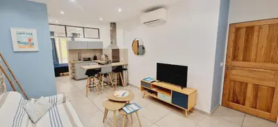 a living room with a television and a kitchen at Superbe appartement en plein coeur d'Ajaccio in Ajaccio