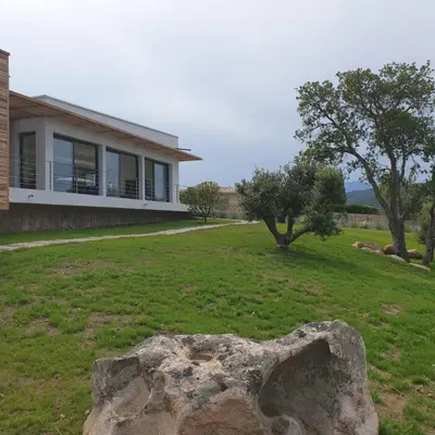 a house with a large rock in the yard at Villa Maria 12 pers piscine chauffée 5 min plage en voiture in Sainte-Lucie de Porto-Vecchio