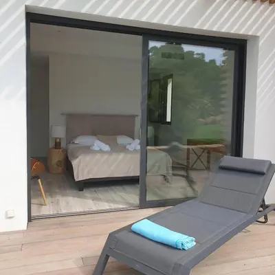a view of a bedroom with a bed and a chair at Villa Maria 12 pers piscine chauffée 5 min plage en voiture in Sainte-Lucie de Porto-Vecchio
